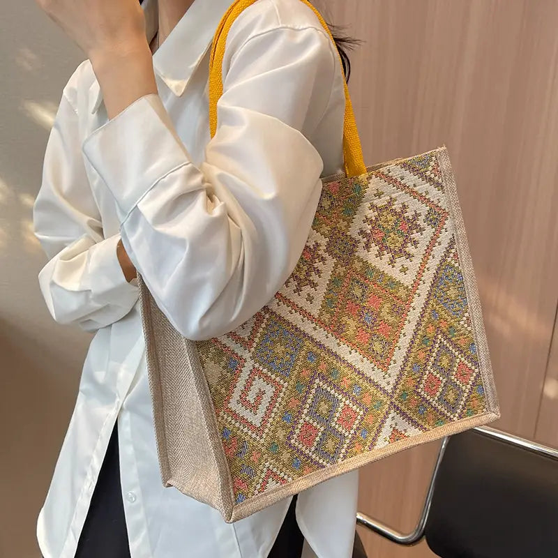 Person holding a colorful patterned bag with a neutral background