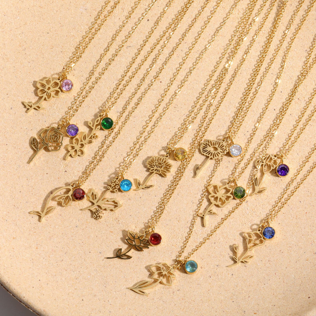 Delicate gold birth flower pendant necklace with a red birthstone charm accent