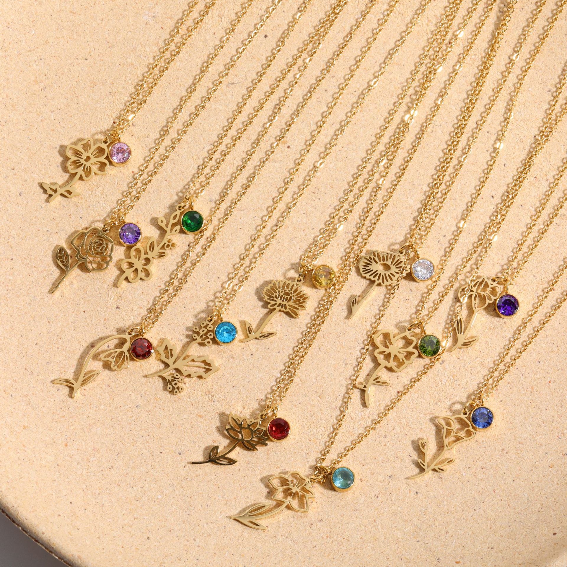 Delicate gold birth flower pendant necklace with a red birthstone charm accent