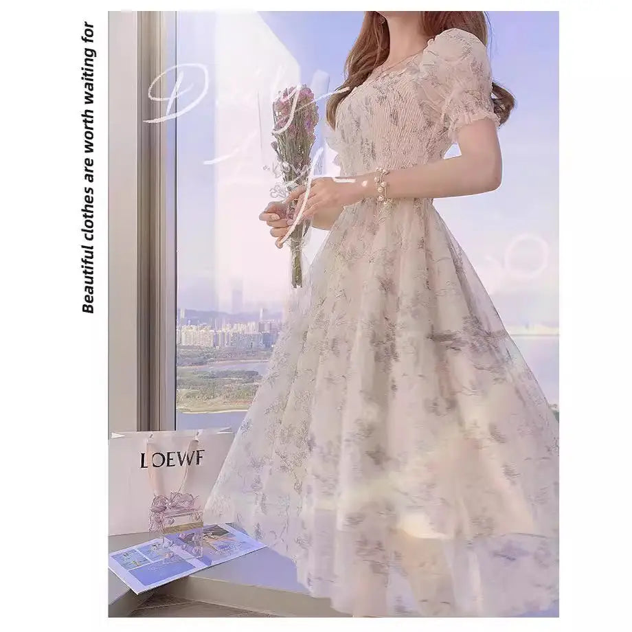 Woman in a floral dress holding flowers by a window with LOEWE branding.