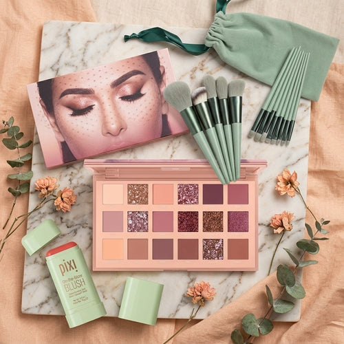 Makeup palette, brushes, and other items on a marble surface with decorative elements.