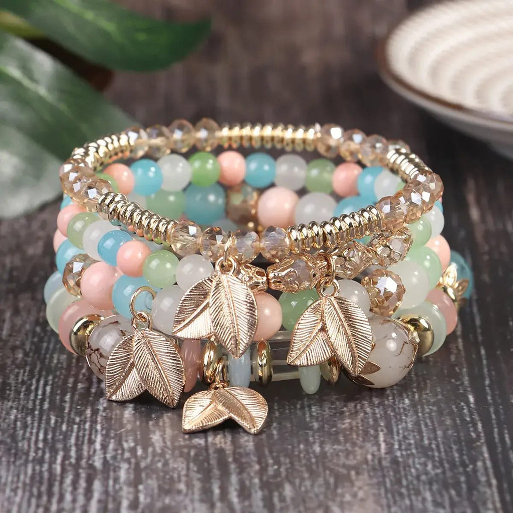 Multistrand beaded bracelet with leaf charms on a wooden surface