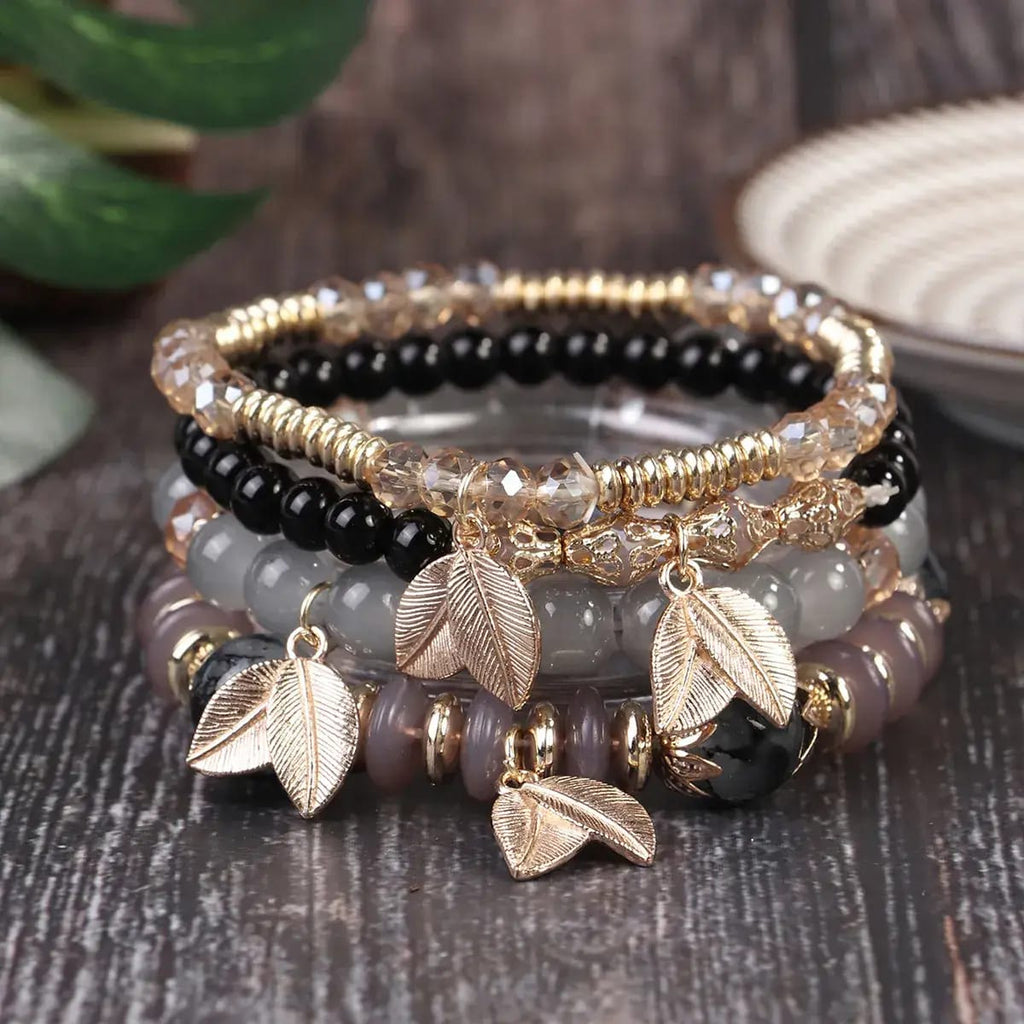 Boho chic 4-piece stackable beaded bracelet in grey and black with gold leaf pendants