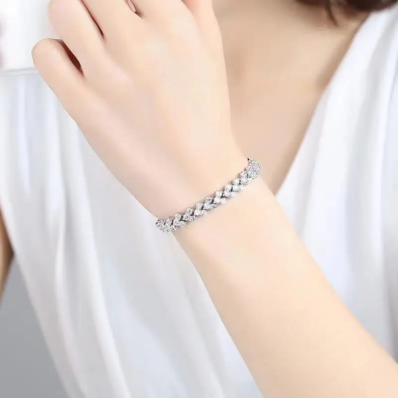 A close-up of a woman's wrist wearing a delicate silver-toned bracelet adorned with small clear stones, paired with a white sleeveless top.