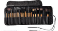 Set of makeup brushes in a black leather case on a white background