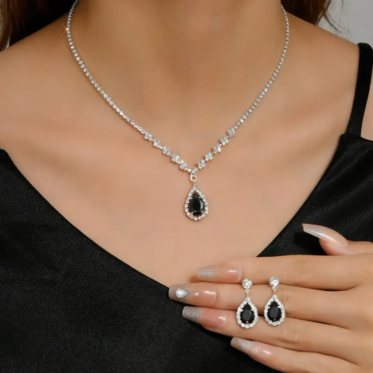 Black teardrop earrings and necklace set on a model wearing a black top.