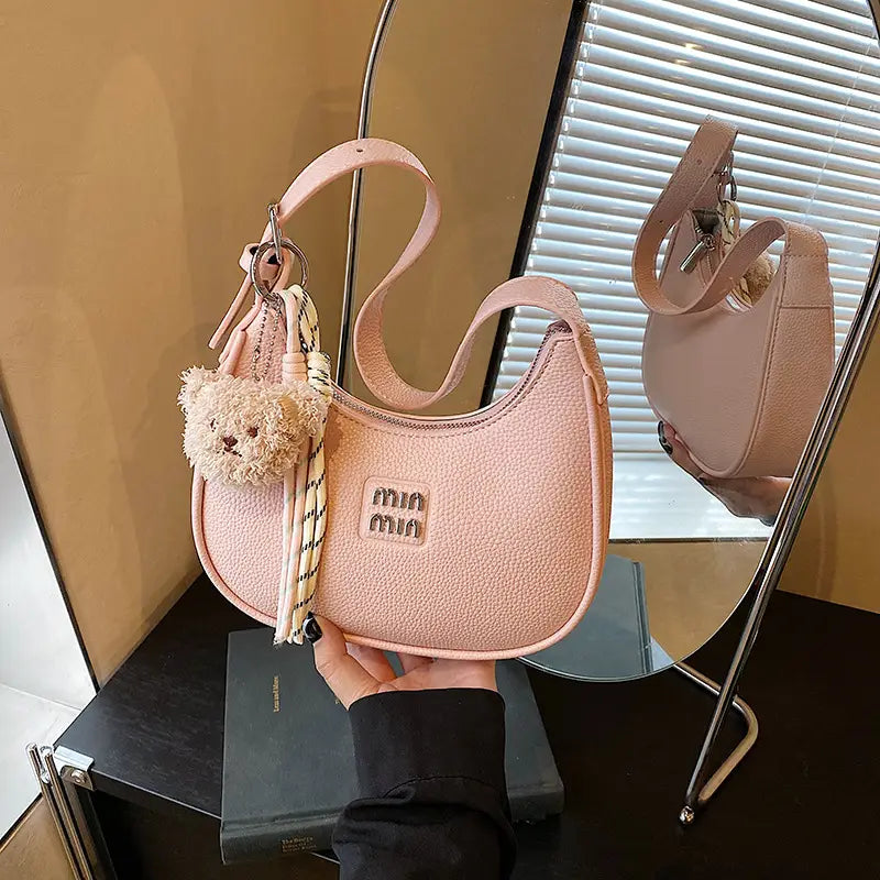  Hand holding a dusty blush pink glitter hobo bag displayed next to a matching purse on a store shelf.