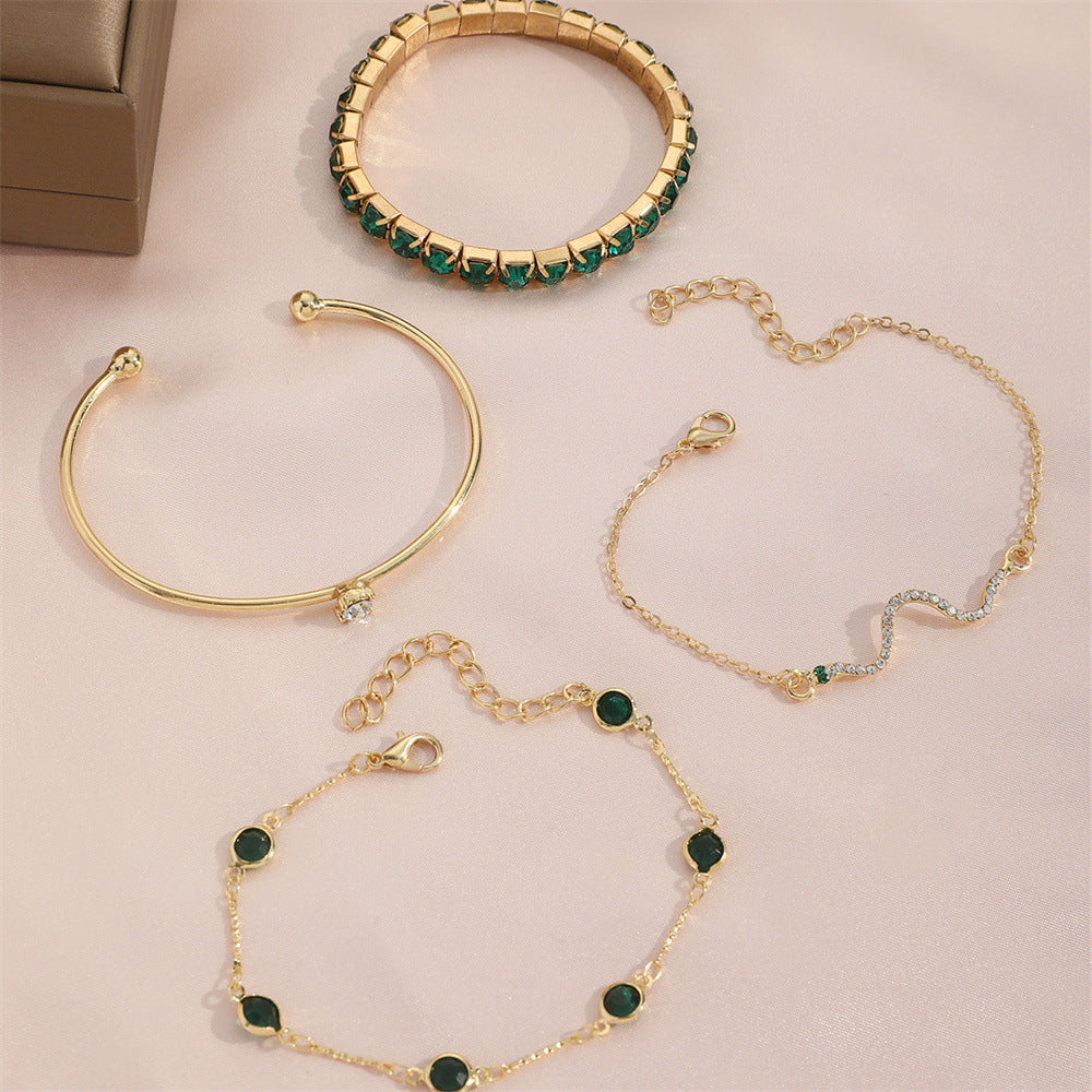 Gold bracelets with green gemstones on a beige background