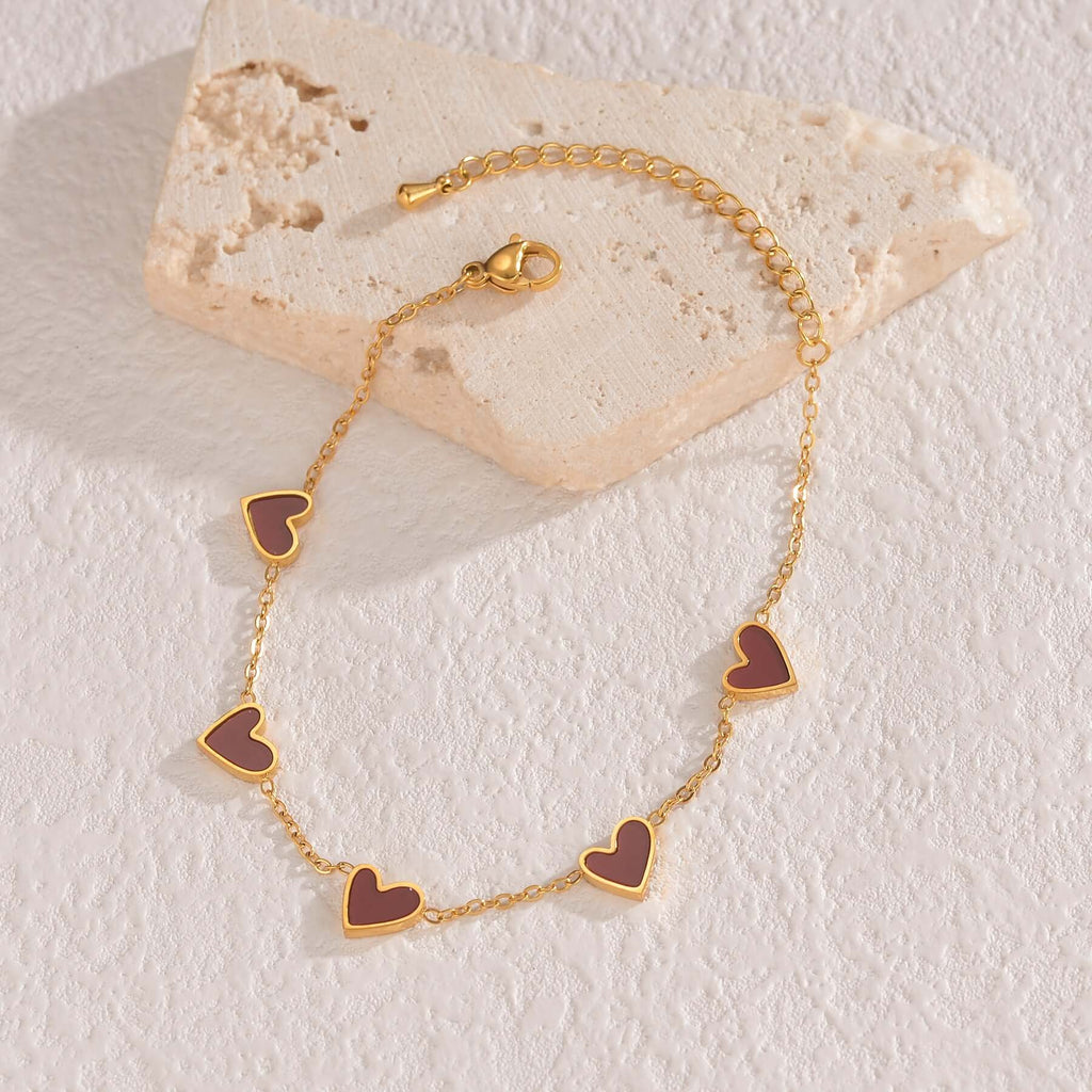 Gold bracelet with heart-shaped charms on a stone surface