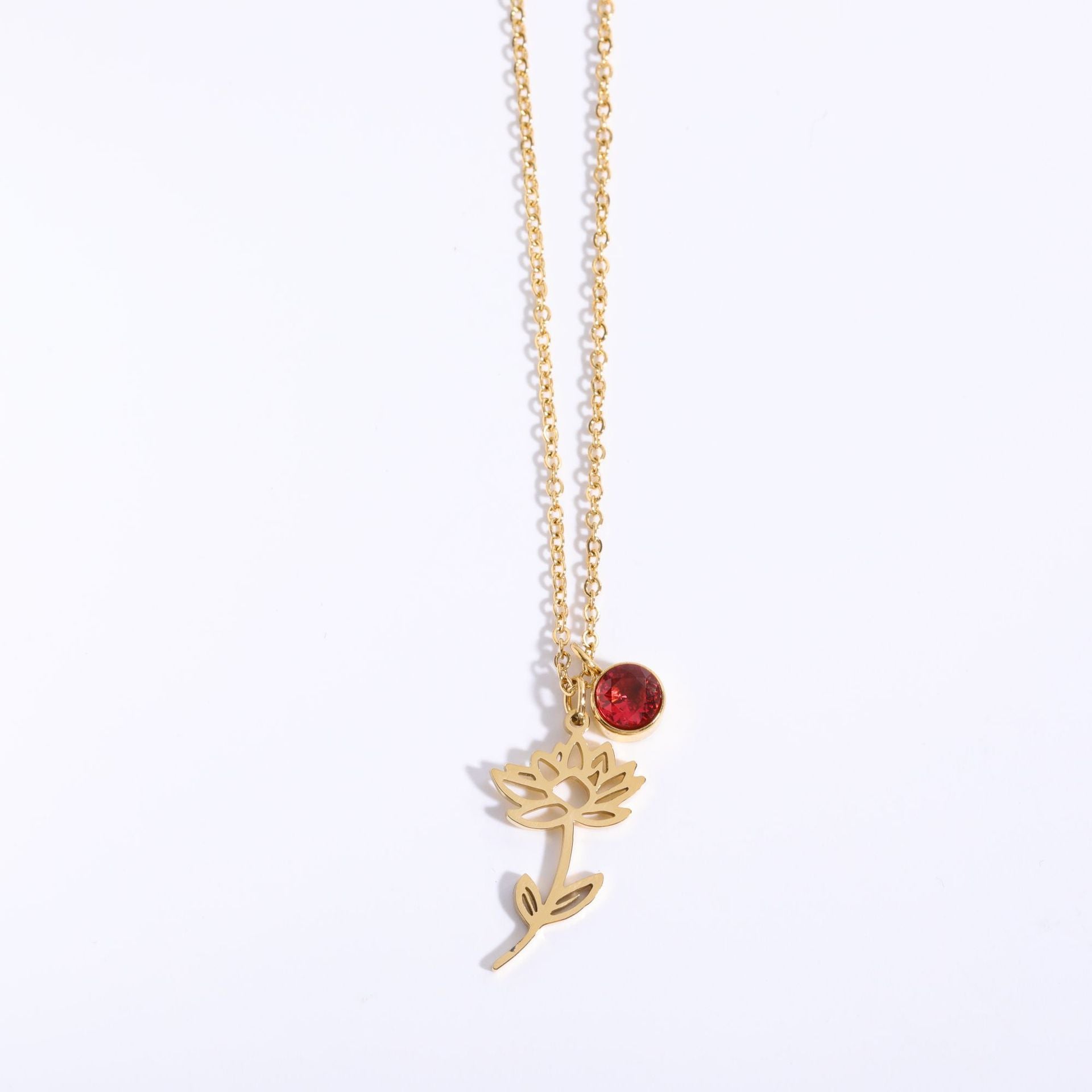 Gold necklace with a flower pendant and red gemstone on a white background
