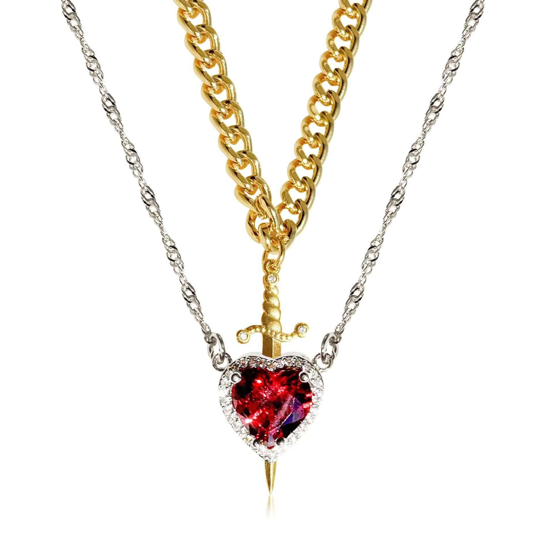 Gold necklace with a heart-shaped red gemstone pendant on a white background