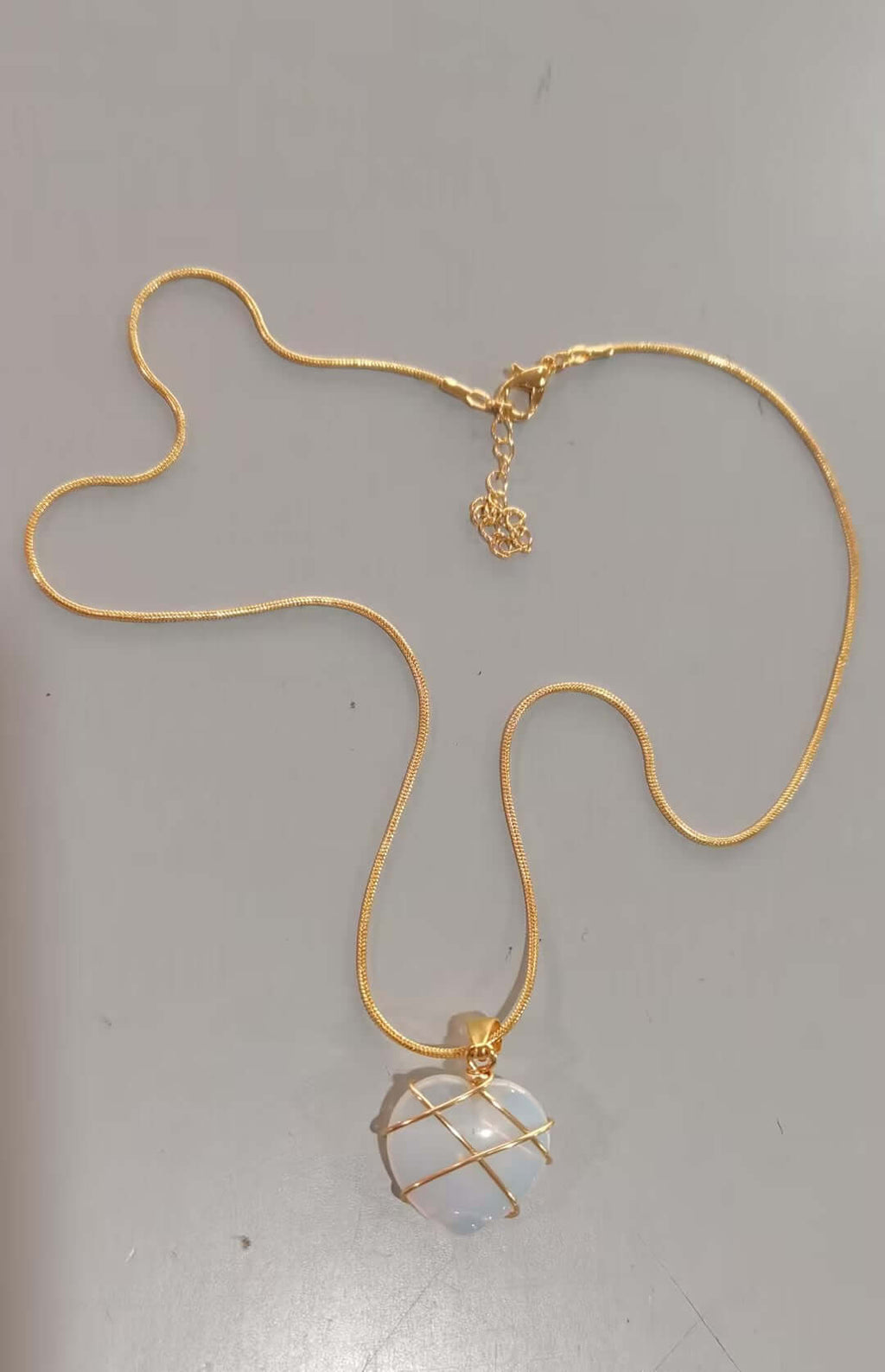 Gold necklace with a pendant on a gray background