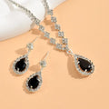 Jewelry set with black teardrop earrings and matching necklace on a peach background