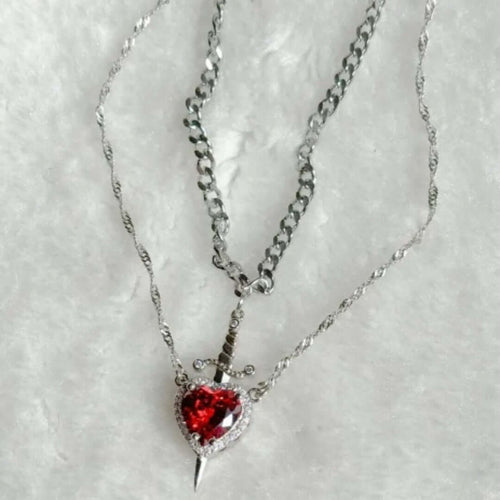 Necklace with a red heart-shaped pendant on a textured white background
