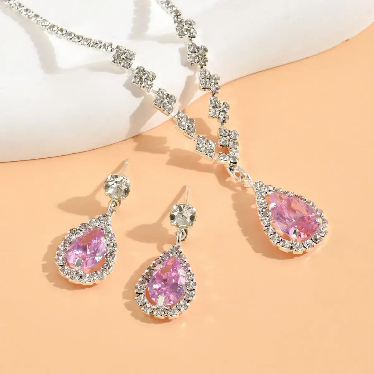 Pink teardrop earrings with silver accents on a peach background