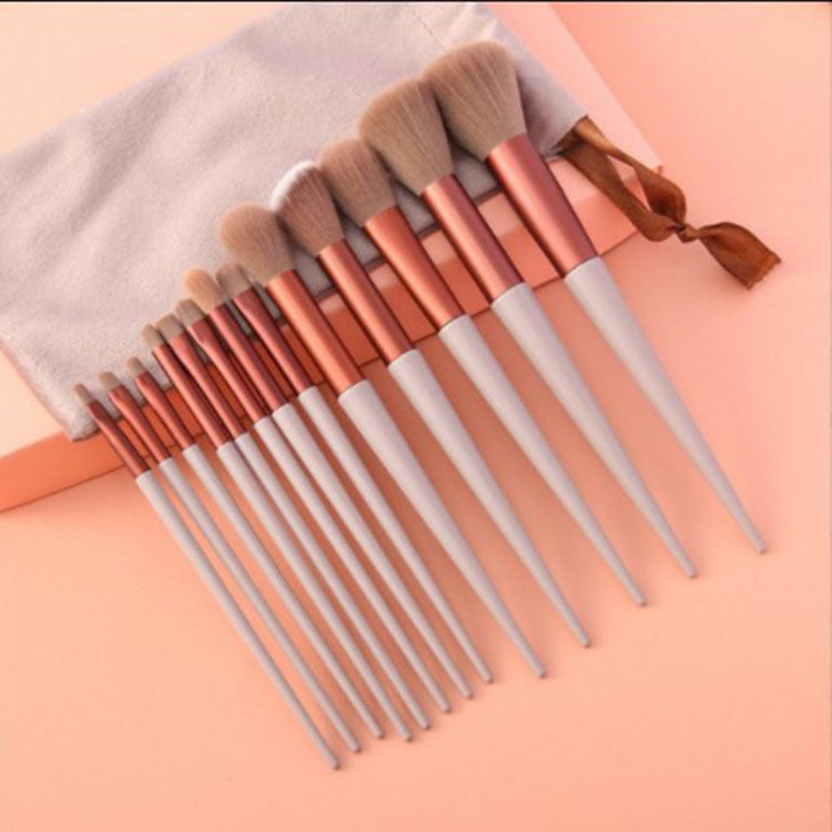 Set of makeup brushes with rose gold and white handles on a pink background