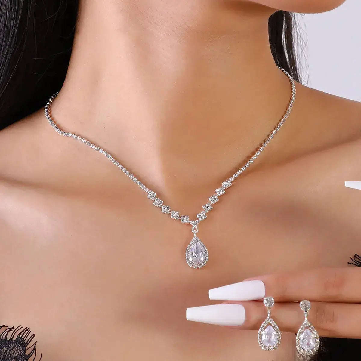 Silver necklace and earrings on a model with a neutral background