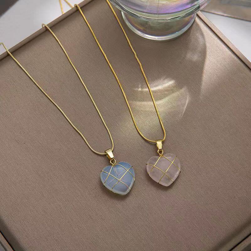 Two gold necklaces with pendant stones on a brown surface