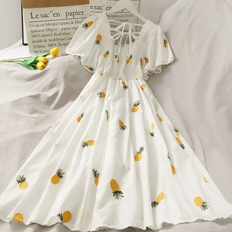 White dress with pineapple pattern on a hanger against a neutral background