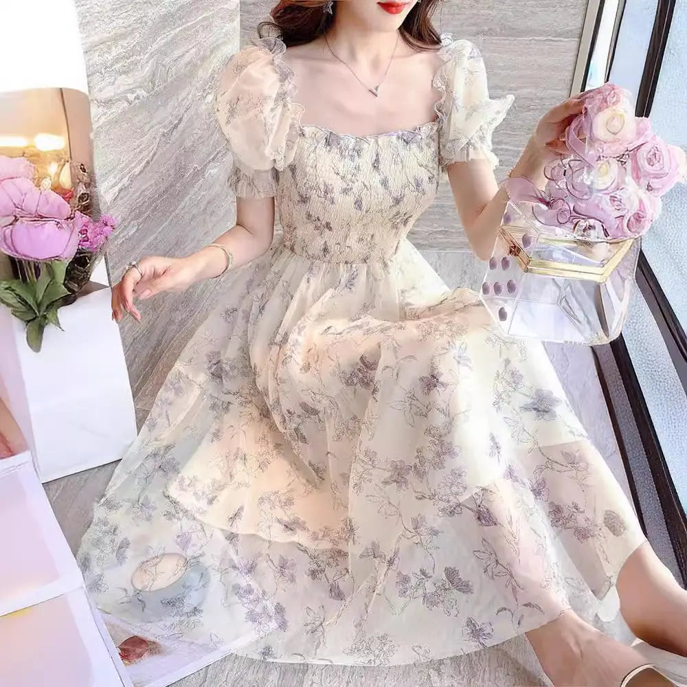 Woman wearing a floral dress holding a pink flower arrangement indoors.