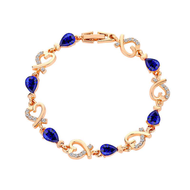  Delicate gold chain bracelet set with royal blue teardrop stones laid flat.