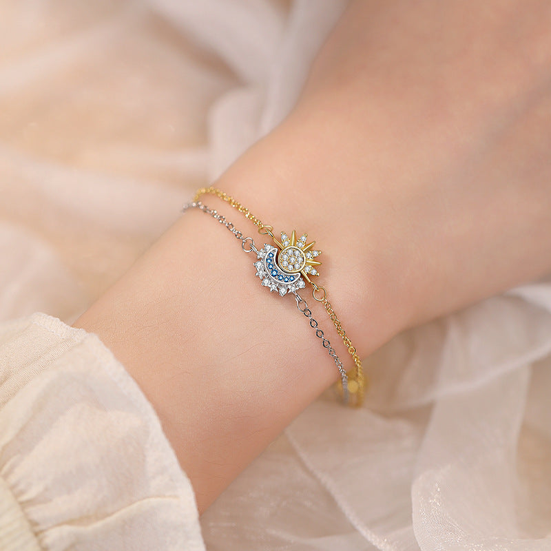 Woman wearing delicate gold celestial sun and blue crystal moon charm bracelet on wrist