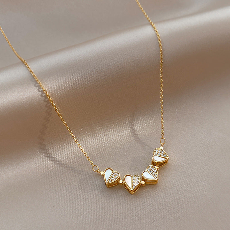 Close-up of gold chain necklace displaying the magnetic pendant open into a row of four connected hearts.