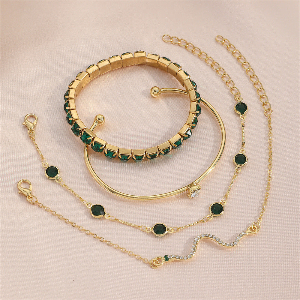 Top-down view of the entire gold-plated chain and emerald bead bracelet collection neatly arranged