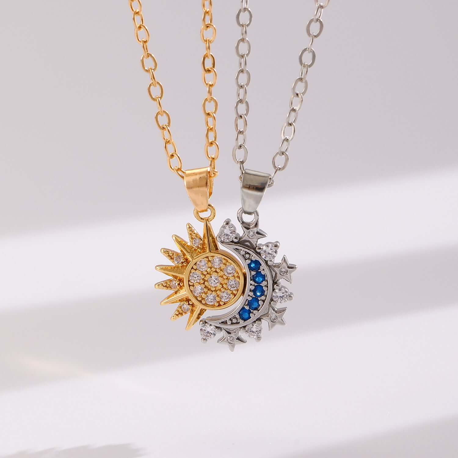 Gold and silver celestial sun and moon charm necklaces displayed on a clean background.