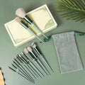 Sage green makeup brush collection arranged neatly on fabric background.