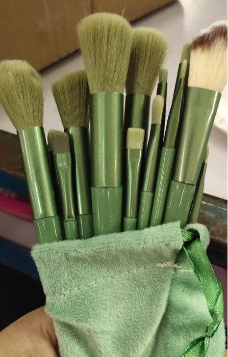 Green makeup brushes standing inside a green drawstring bag.