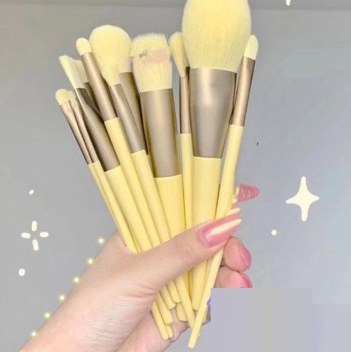  Hand holding a bundle of soft yellow makeup brushes.