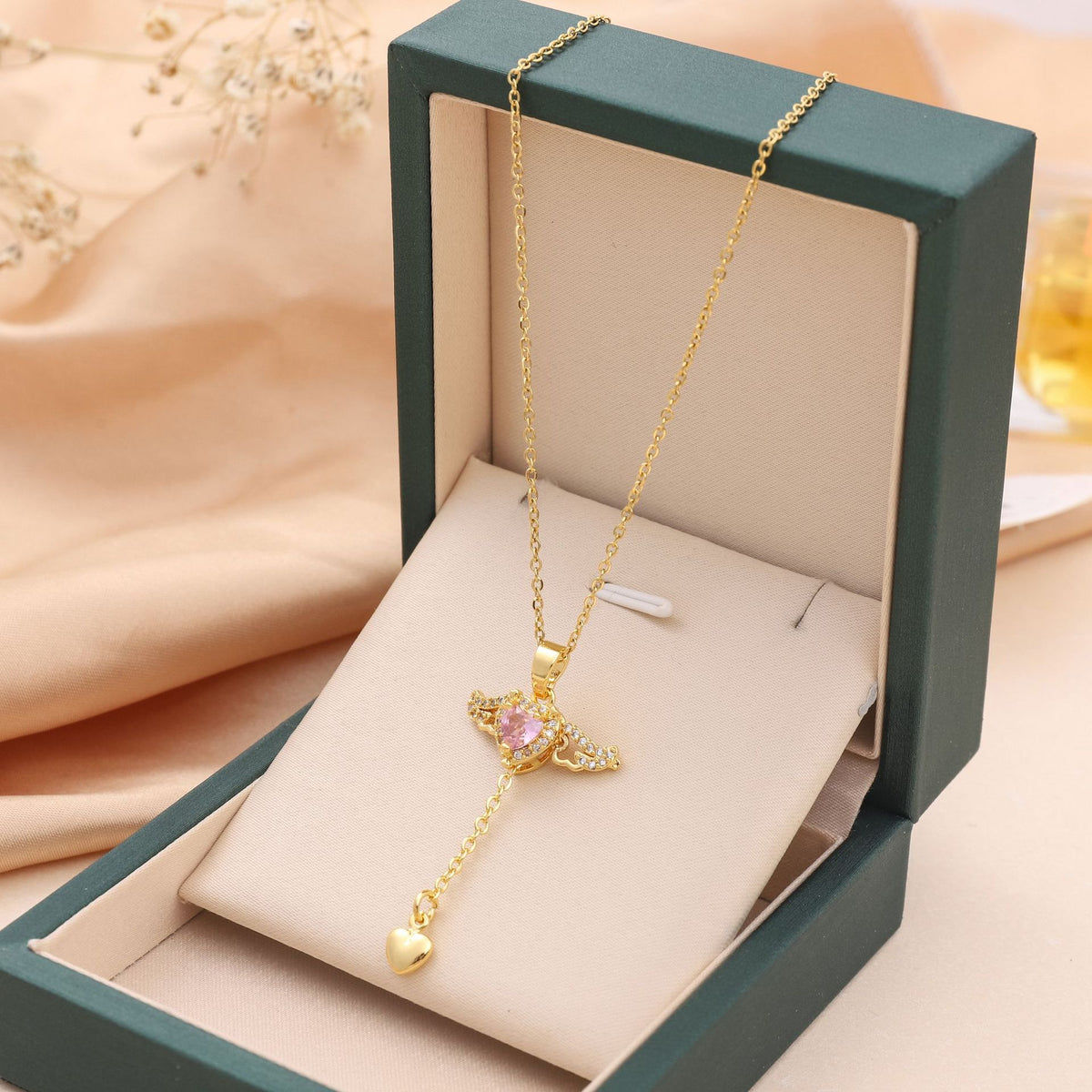  Pink heart wing pendant necklace displayed inside an open dark green gift box.