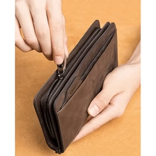 Hands opening main zipper compartment of black long wallet