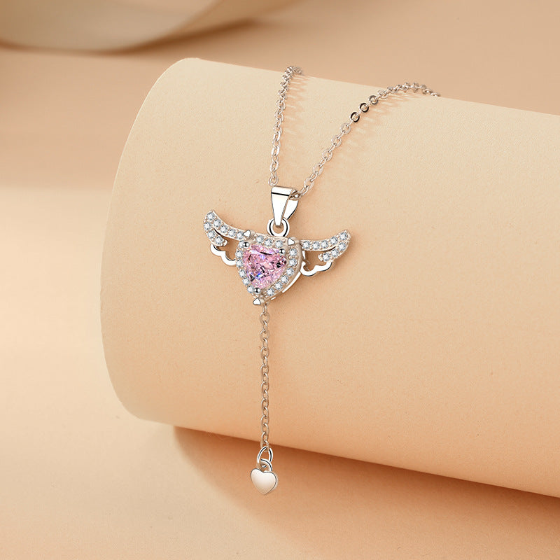 Silver drop chain necklace with pink heart pendant wrapped around a jewelry display roll.