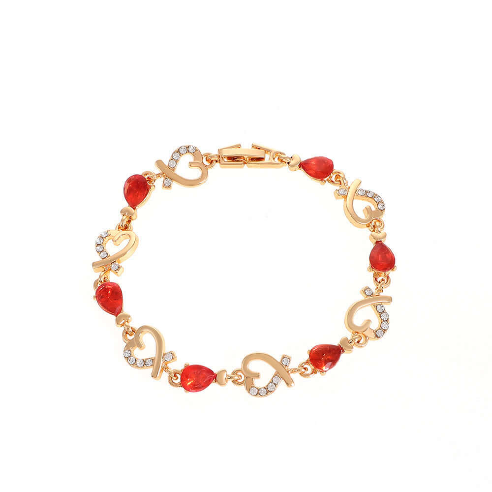 Elegant gold bracelet with red teardrop crystal links shown against a white background.