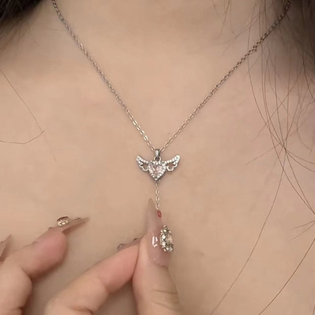 Close-up of the silver pink heart angel wing necklace worn on a neckline.