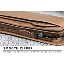 Close up view of smooth zipper closure on brown leather clutch wallet
