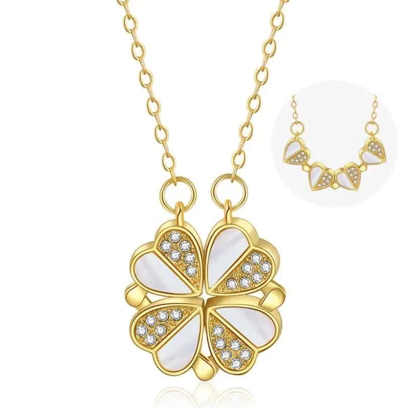 Sparkling crystal four-leaf clover pendant lying on smooth grey silk fabric.