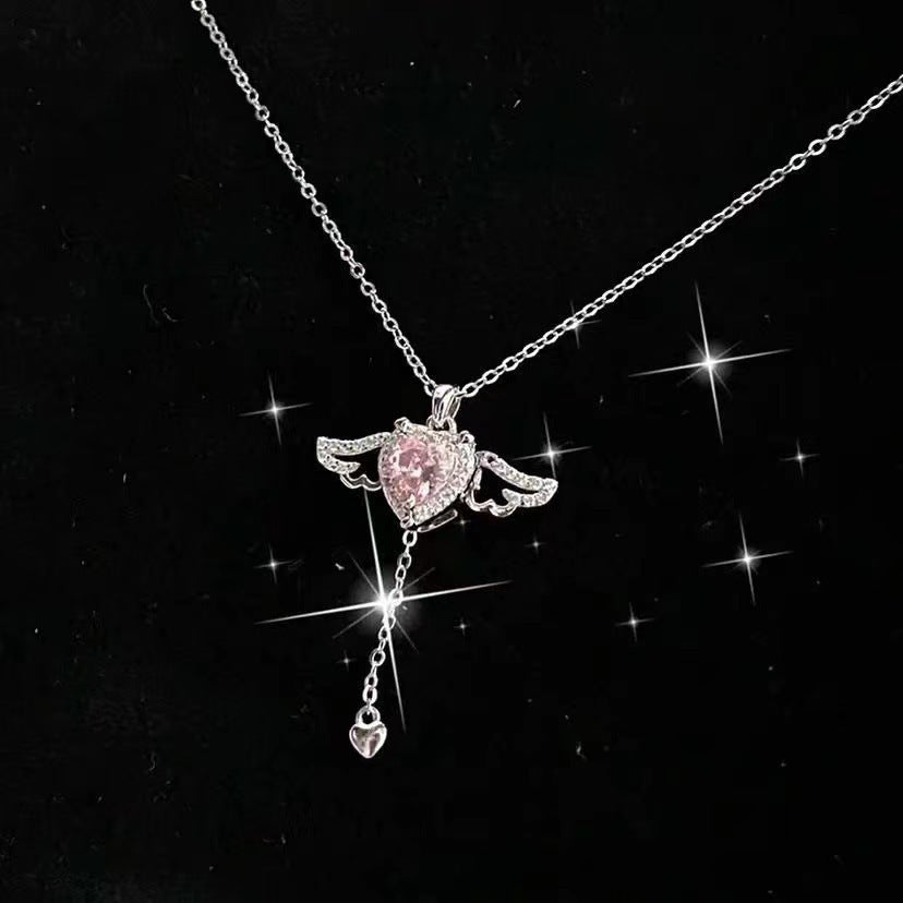 Sparkling silver angel wing necklace with pink heart center on a sleek black background with shimmer effects.