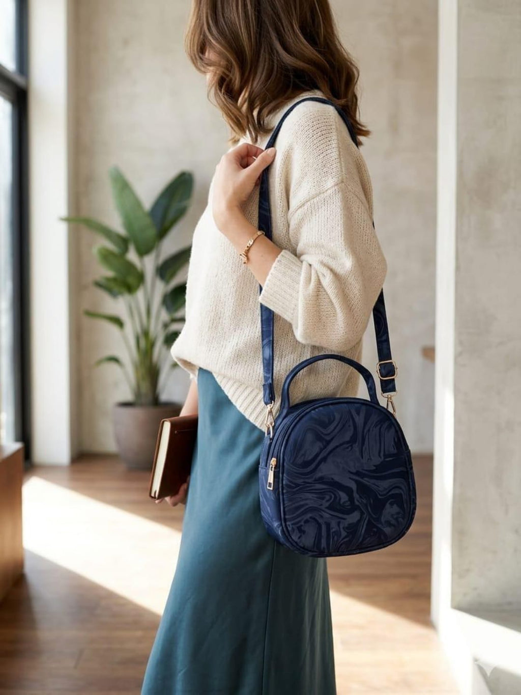 Woman wearing stylish blue round crossbody bag with adjustable strap