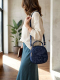 Woman wearing stylish blue round crossbody bag with adjustable strap