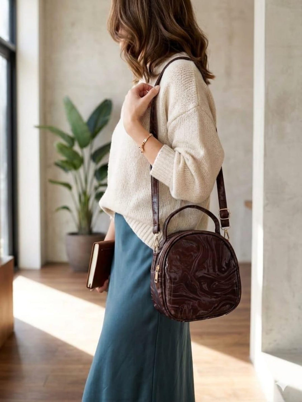 Woman wearing chocolate brown round crossbody handbag