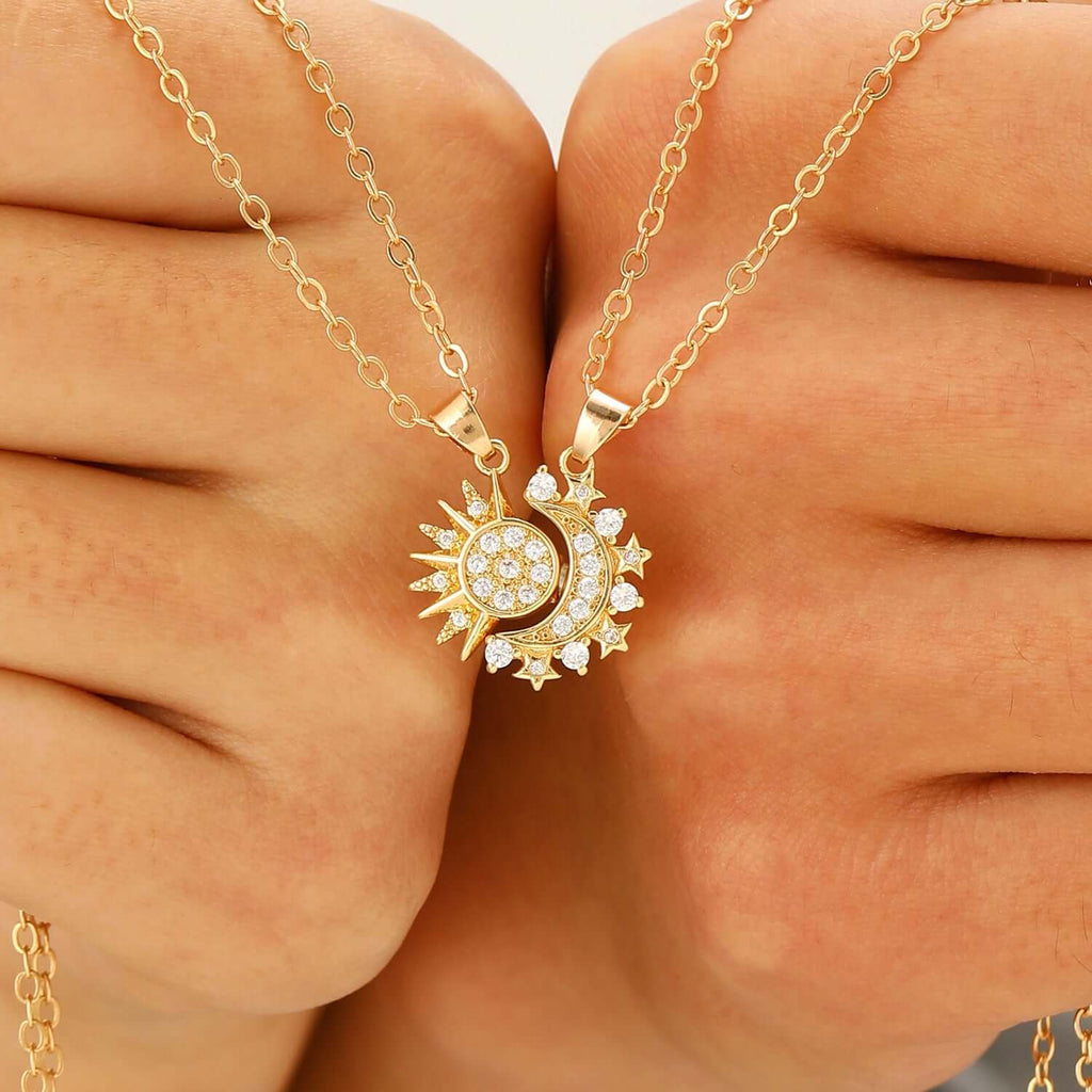  Close up of two hands holding the sun and moon pendants interlocking together.