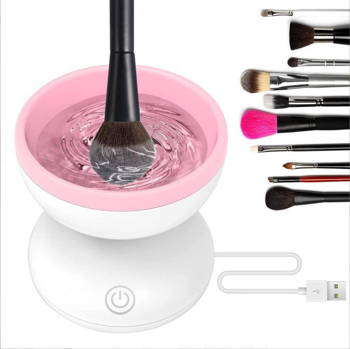White electric makeup brush cleaner with a pink top ring washing a cosmetic brush inside water.